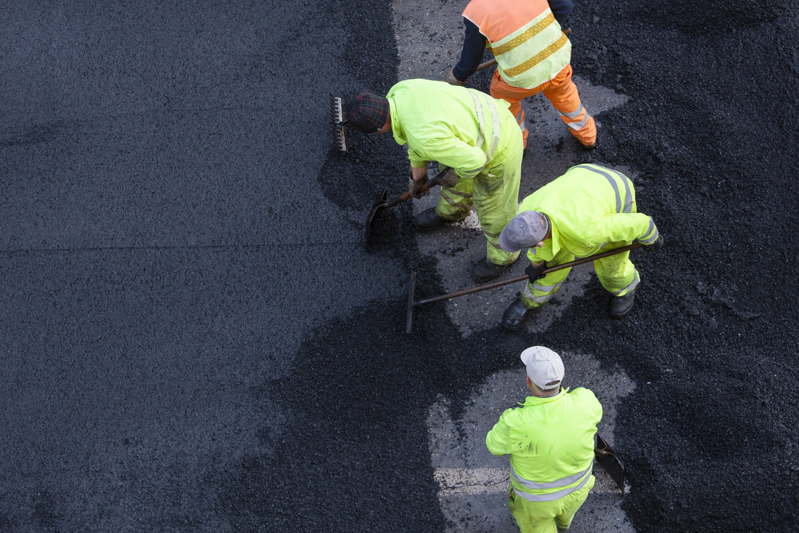 Workers during Asphalting Road Work on city street. Asphalt paving. High angle view. Copy space